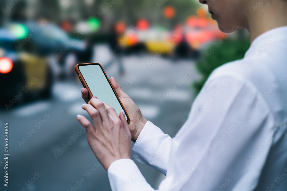 Crop unrecognizable woman chatting online on smartphone while standing on roadside