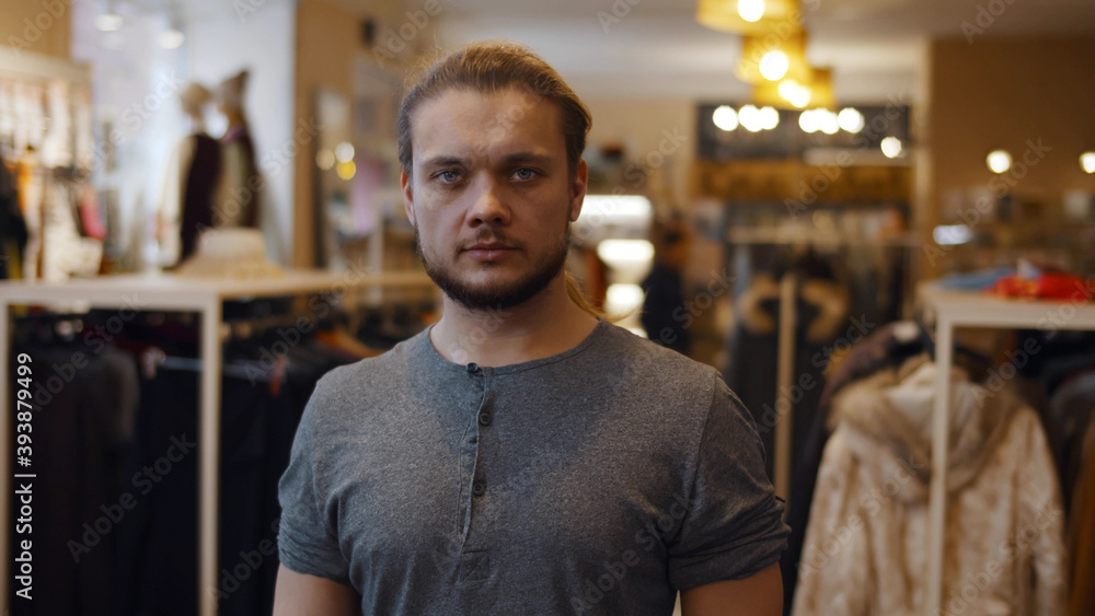 Obraz premium Young handsome confident man looking at camera standing at clothing store