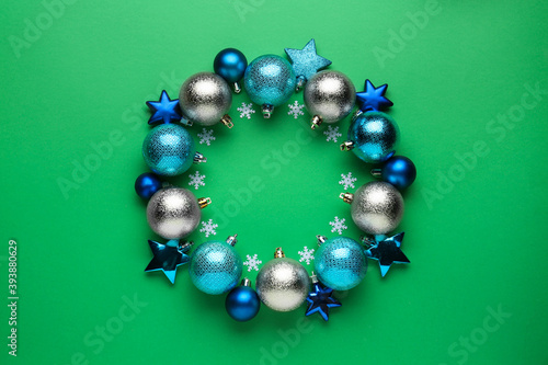 Beautiful festive wreath made of different Christmas balls on green background, top view