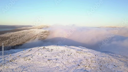 Wallpaper Mural flying in a clear sky above low clouds over a snow-covered  mountain illuminated by the rays of the sun Torontodigital.ca