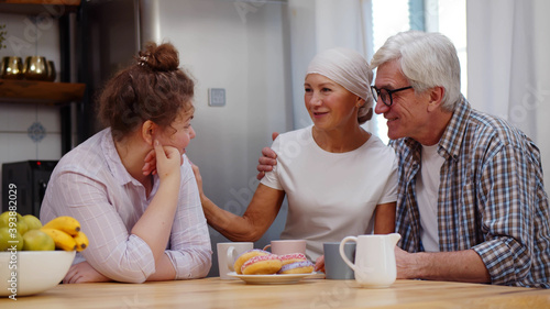 Foto Adult daughter and senior husband supporting woman with cancer having coffee tog