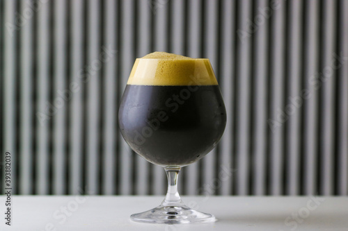Canvas Print Glass of dark craft beer with creamy head