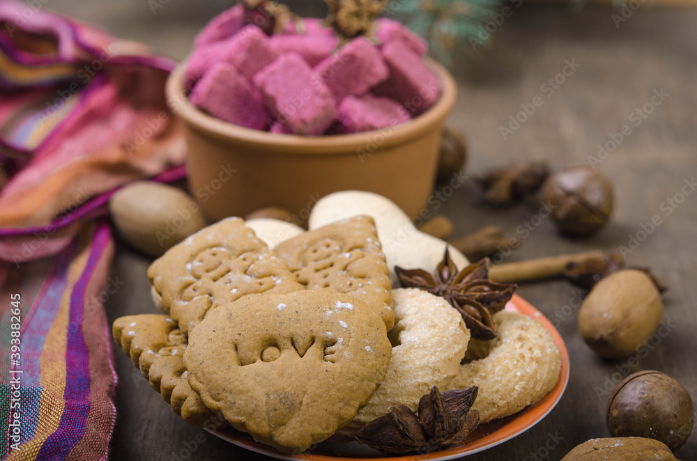 Various gingerbread cookies in an orange saucer and sugar in a bowl. Various gingerbread cookies in an orange saucer and sugar in a bowl.