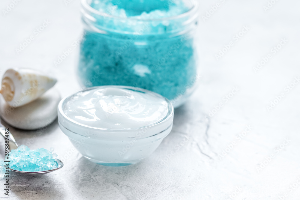 blue bath salt, body cream and shells for spa on white table background blue bath salt, body cream and shells for spa on white table background