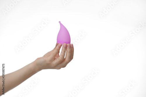 Young woman hand holding a pink menstrual cup - white background. Gynecology concept. photo