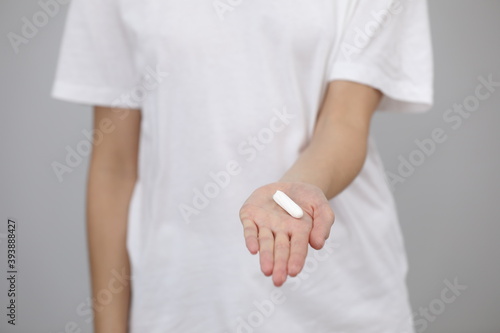 woman dressed in white t shirt, holding a clean tampon in her hands, close-up. female hygiene products, menstruation