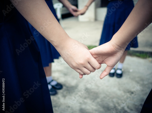 The hands of a female high school student hold on together.