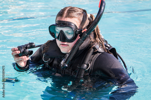 Scuba dive training in a pool, a student with a wetsuit and dive mask on and regulator in her hand close up.