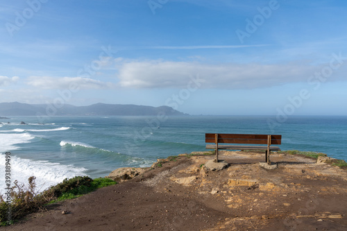 scenic viewpoint with wooden bench on beautiful ocean coast with high cliffs and big waves