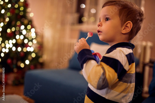 A little boy with lollipop at New Year eve at home. Together, New Year, family, celebration