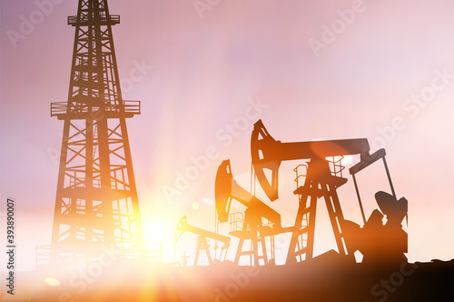 Darck silhoutte of oil rig and pumps during sunset.