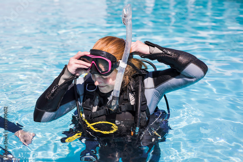 Scuba dive training in a pool one student putting her dive mask on.
