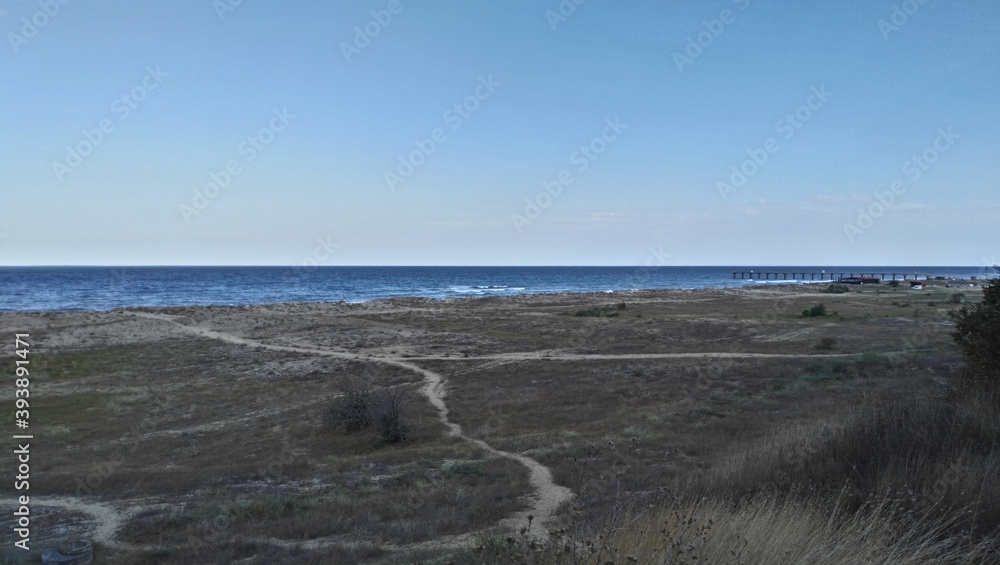 Distant strip of sea water
Bulgaria, Black Sea. Summer day. Coastal vegetation by the sea. The ground is grass. Well-worn sandy paths go to the sea