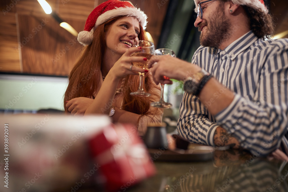 A young couple in love toasting at Xmas celebration at a restaurant. Together, New Year, celebration A young couple in love toasting at Xmas celebration at a restaurant. Together, New Year, celebration