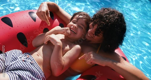 Mother tickling son in swim ring in a pool
