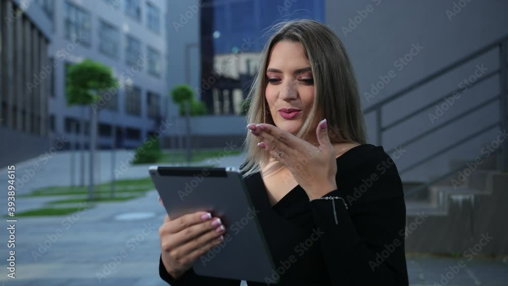 Beautiful young woman using tablet in the city. Business lady holds digital devices pc. Businesswoman and pad. Sitting on a bench outside an office district. Gap between teeth Beautiful young woman using tablet in the city. Business lady holds digital devices pc. Businesswoman and pad. Sitting on a bench outside an office district. Gap between teeth