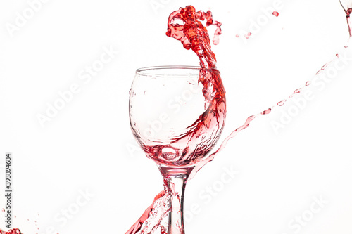 splash and flow of red wine in a glass on a white background with reflection