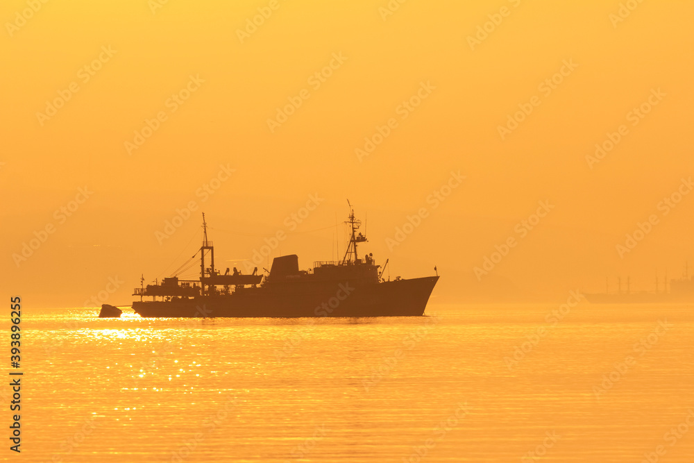 Silhouette of the ship in the morning at dawn in the fog. The Eastern Bosphorus strait between Tokarevsky lighthouse and the Russian island in Vladivostok.