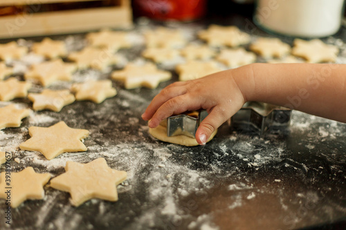 little girl bakes cookies in the form of stars. Christmas cookies.