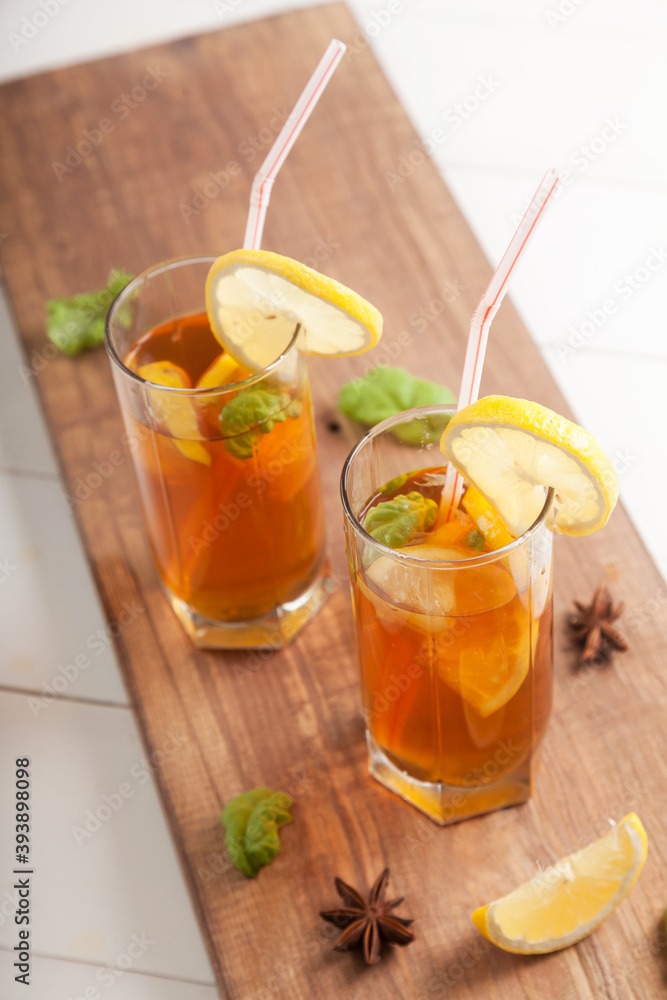 Two glasses with kombucha and lemon slices, straws and star anise on a wooden table. Two glasses with kombucha and lemon slices, straws and star anise on a wooden table.