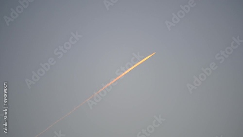 Airplane flying in the sky and its contrail at sunset