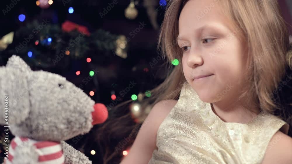 A smile little girl in a pink dress lonely looks at his stuffed toy. Spoiled holiday. A brooding child A smile little girl in a pink dress lonely looks at his stuffed toy. Spoiled holiday. A brooding child