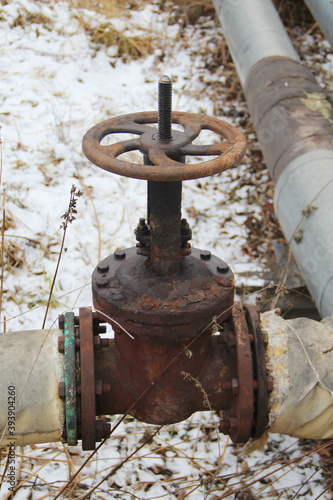 Old damaged and rusty iron oil pipe valve wheel. Metal, pipeline and mechanic concept. An old iron valve on a gas pipe. A valve to cover the pipe with a round handle