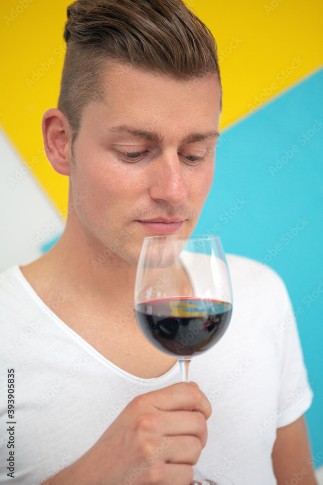 blond man holding a glass of red wine on colorful background blond man holding a glass of red wine on colorful background