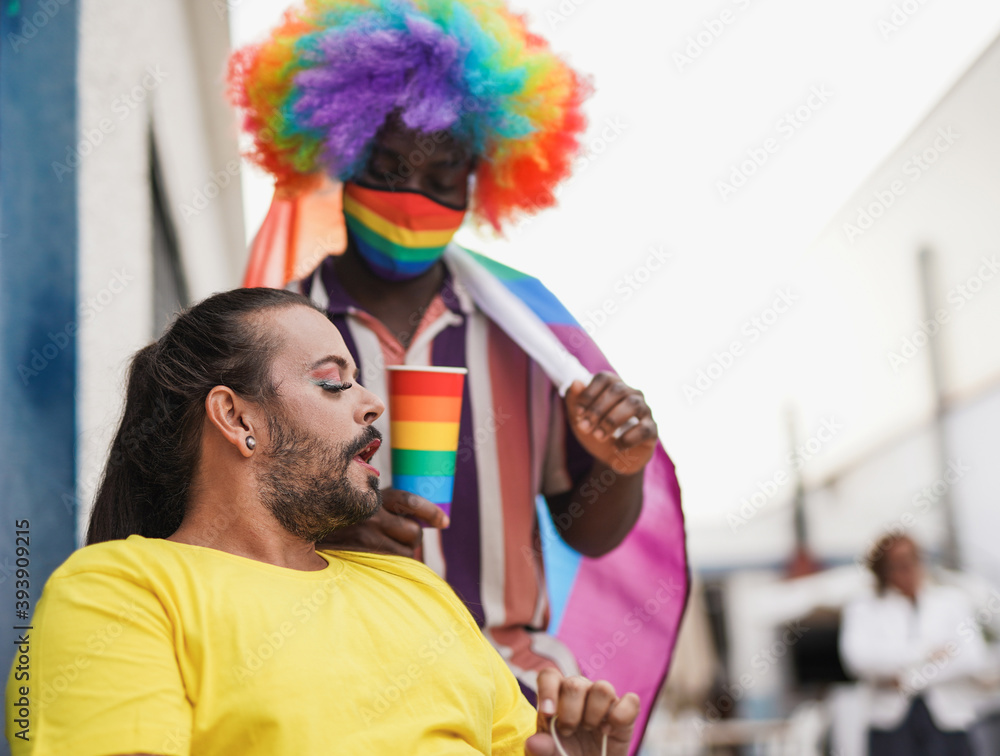 Gay men at gay pride parade - Drag queen and african gay man with lgbt rainbow flag