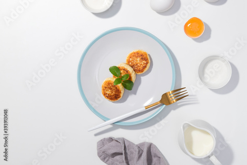Cottage cheese, eggs, cream and yougurt on a white background - Flat lay with curd pancake - Recipe