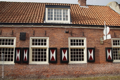 Old house, masonry and shuttered windows of a 1787's Dutch building. Wooden red and white shutters. Netherlands, November