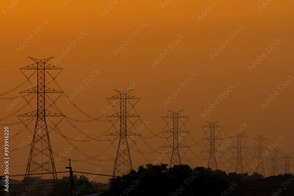 High voltage poles line the orange evening light.