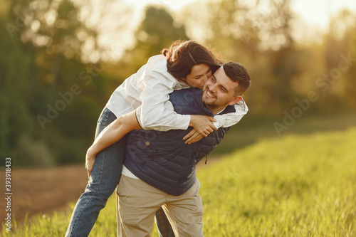Couple in a field. Woman in a white shirt. Sunset background.