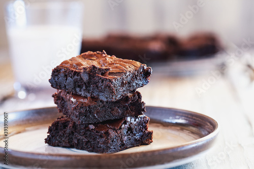 Cuadro en lienzo Fresh homemade fudgy brownies stacked on a saucer over a white rustic wooden table