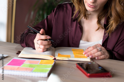 Female manager in purple blouse noting some information in notepad