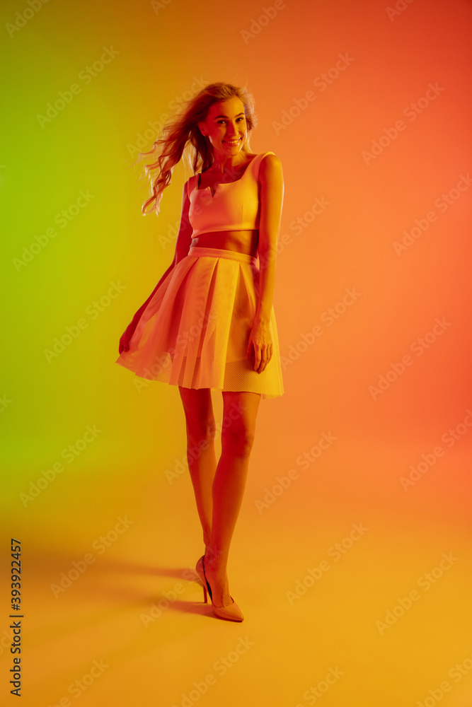 Beautiful seductive girl in fashionable, romantic outfit on bright gradient green-orange background in neon light. Full-length portrait. Copyspace for ad. Summer, fashion, beauty, emotions concept. Beautiful seductive girl in fashionable, romantic outfit on bright gradient green-orange background in neon light. Full-length portrait. Copyspace for ad. Summer, fashion, beauty, emotions concept.