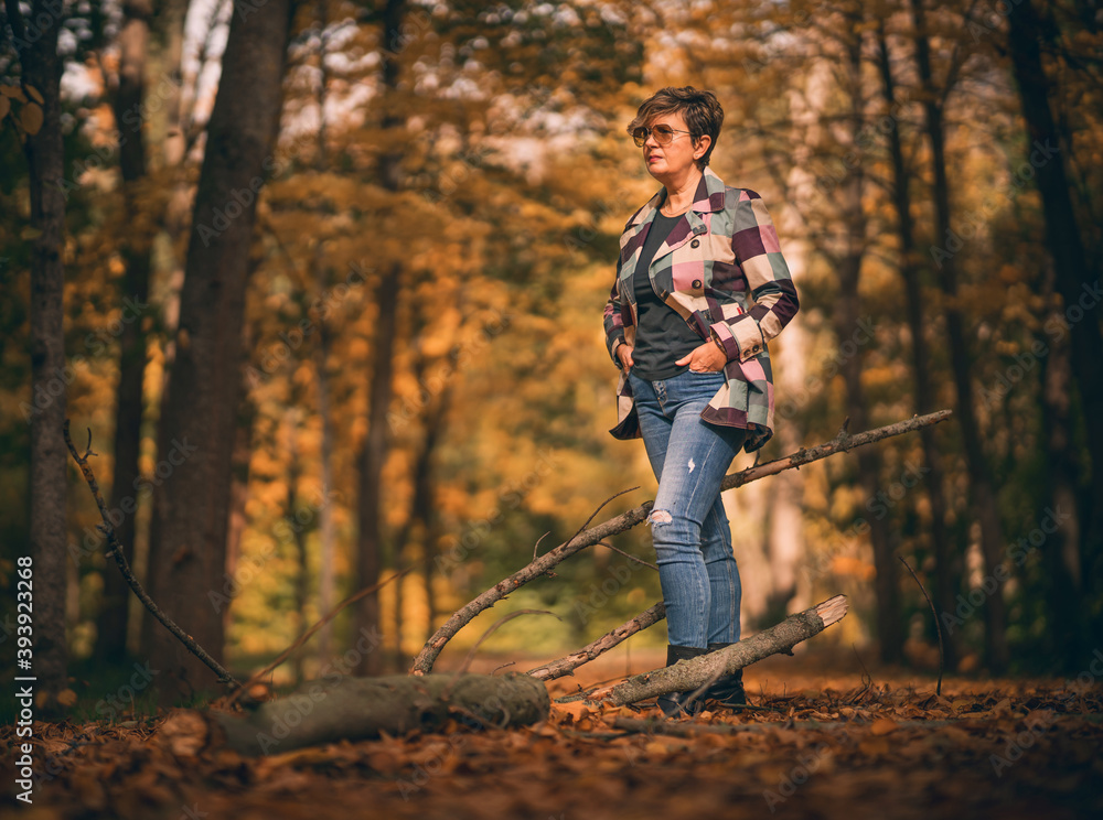 Mujer paseando por un parque al aire libre y con el móvil en las manos 