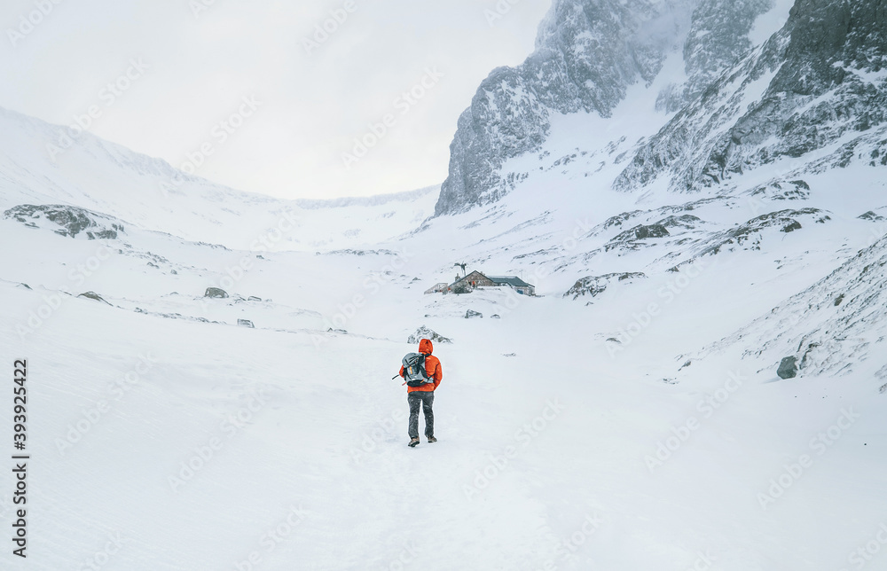 Alone mountaineer has a solo winter Ben Nevis 1345m summit approaching in high mountains on windy snowy weather at Highlands of Scotland.