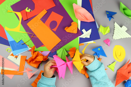 Children's hands make origami crafts from colored paper