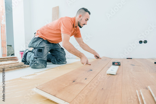 A Male Worker install wood floor on a house © karepa
