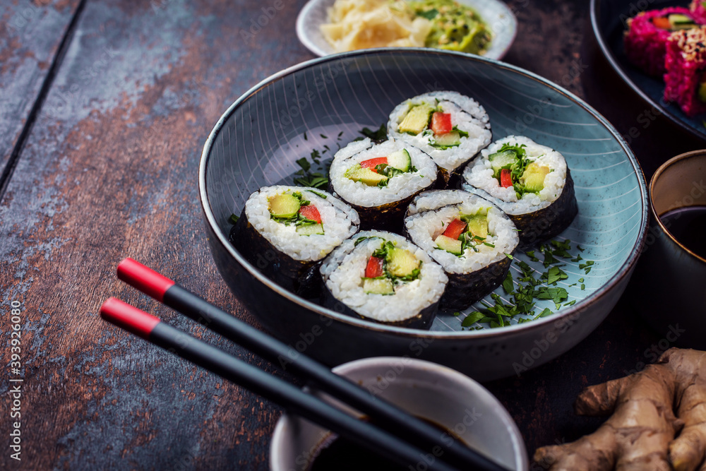 Delicious rolls, sushi and maki on a dark wooden Board with chopsticks. On black rustic background Delicious rolls, sushi and maki on a dark wooden Board with chopsticks. On black rustic background