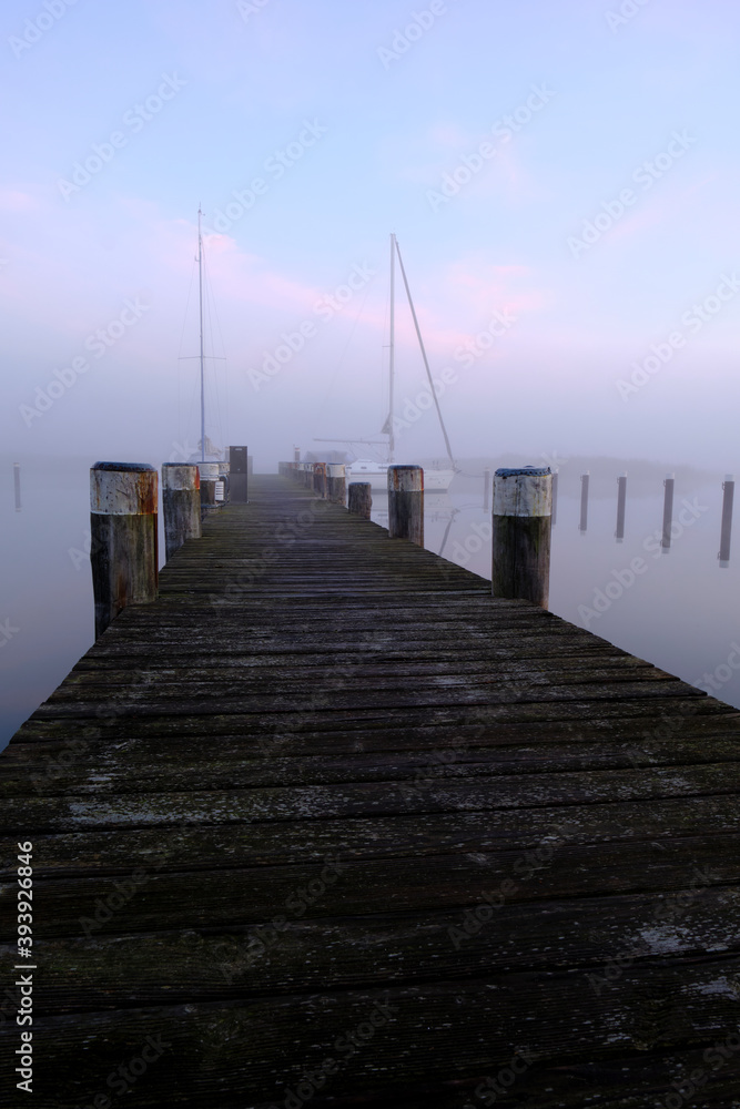 Fototapeta premium Sonnenaufgang im Nebel über dem Hafen Prerow am Prerowstrom, Halbinsel Fischland-Darss-Zingst, Mecklenburg-Vorpommern, Deutschland