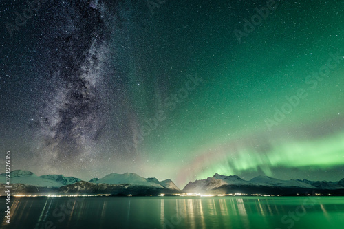 Schilderij op canvas The Milky Way and northern lights above a Norwegian fjord with snow-covered moun