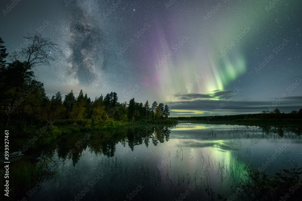 The Milky Way and Auroras above a still lake with reflections