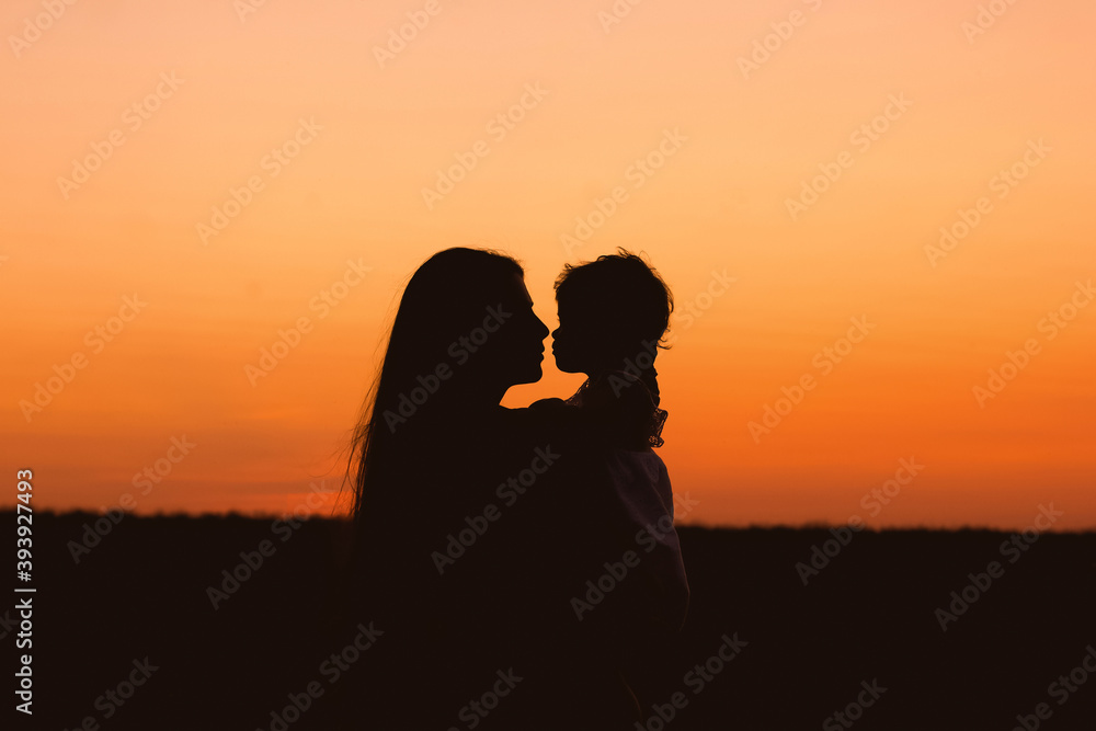 Mother and daughter in a deep moment of love during sunset at beach - Concept of union and tender connection between a young mama and his lovely child