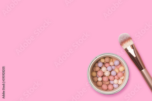 Face powder and brush on a pink background. Meteorites for makeup.