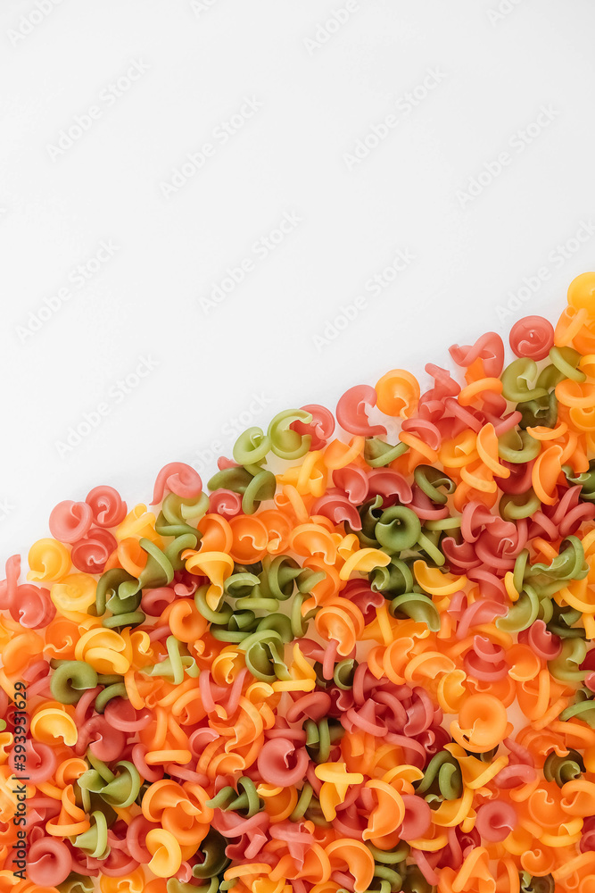 Multicolored pasta scattered on a white background. Top view. Copy, empty space for text Multicolored pasta scattered on a white background. Top view. Copy, empty space for text