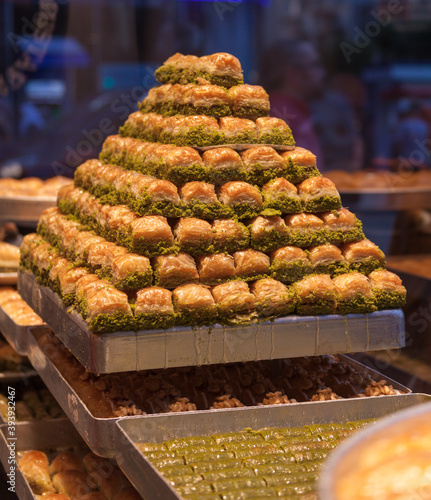 Traditional fresh baklava with pistachio nuts, pyramid shop display. Baklava's water is dropping over the other baklavas under that.