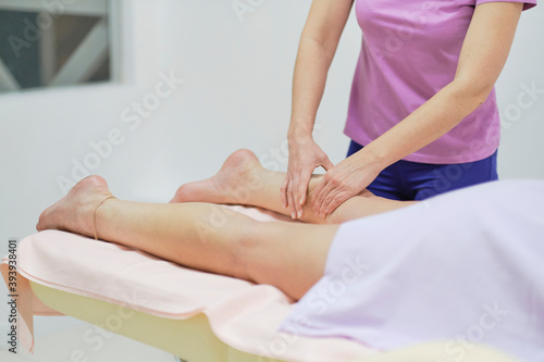 Detail of hands massaging human calf muscle.Therapist applying pressure on female leg. Beautiful girl enjoying treatment procedure, concept of body care and cosmetology