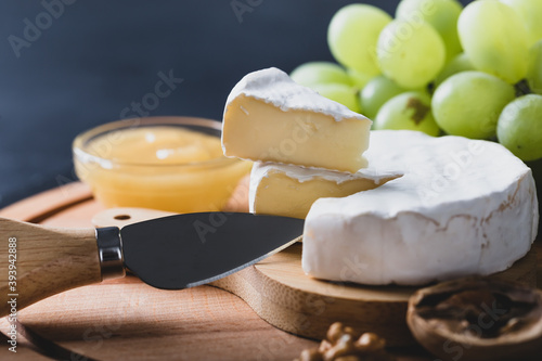 Sliced Camembert served with knife, honey and grape